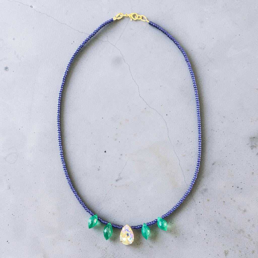 This elegant piece combines rich navy seed beads, shimmering crystal drop accents, and AA+ Green Onyx drop briolettes to create a sophisticated and eye-catching design.
