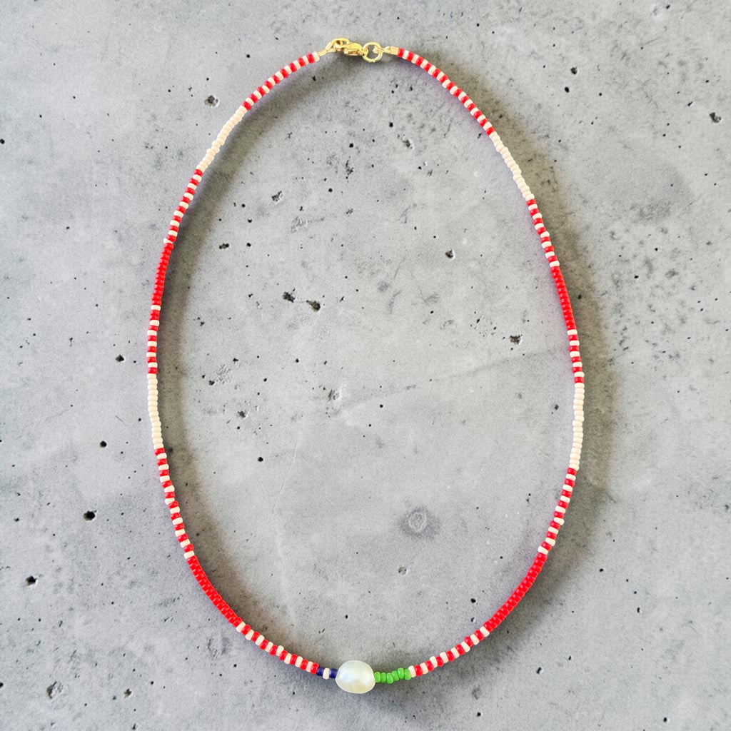 This unique piece combines red, soft pink, and green seed beads with delicate lapis stone accents and a genuine pearl detail, creating a graceful balance of colour, texture, and elegance.