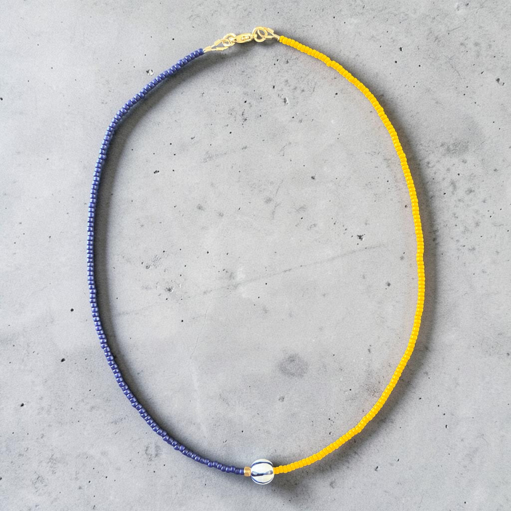 deep navy and warm yellow seed beads, finished with a distinctive central ceramic bead